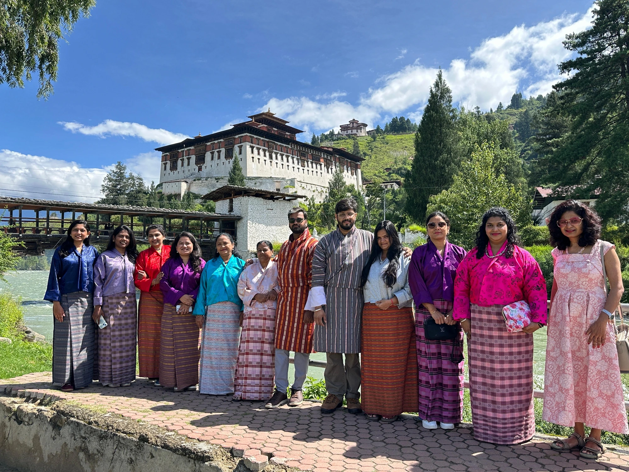 A TrekPanda Bhutan batch dressed in traditional kiras and ghos, posing in front of Paro Dzong